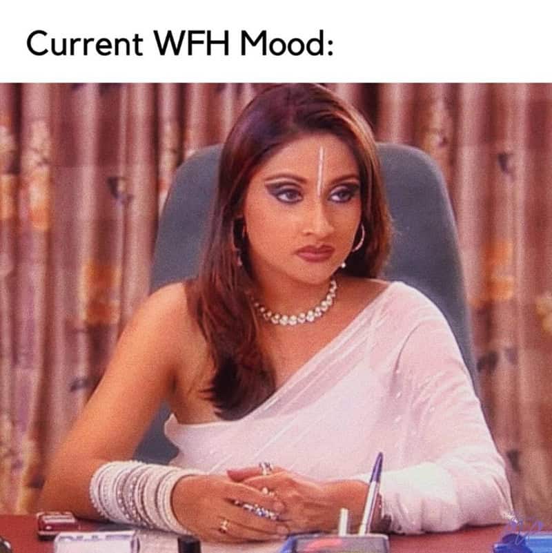 Woman with serious expression, wearing traditional Indian attire, sitting at a desk.
