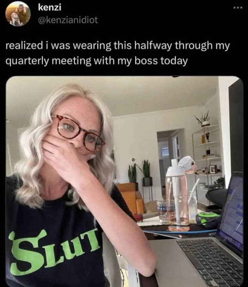Woman with glasses wearing a black T-shirt with 'Slut' written on it, covering her mouth with her手.