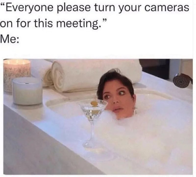 Woman in a bathtub with a cocktail glass, looking surprised, during a virtual meeting.