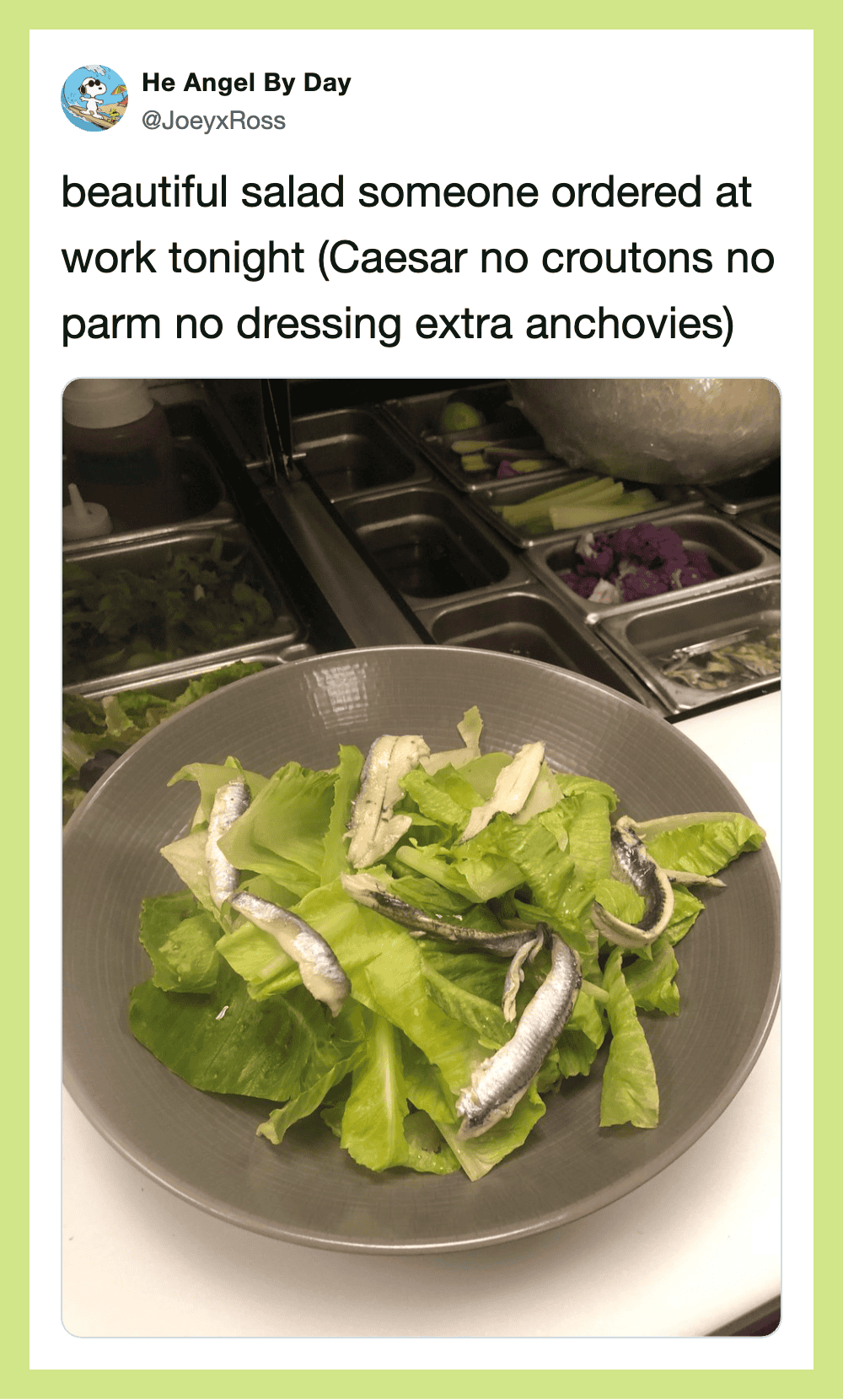 Salad with lettuce and anchovies in a bowl at work, with salad bar in background.