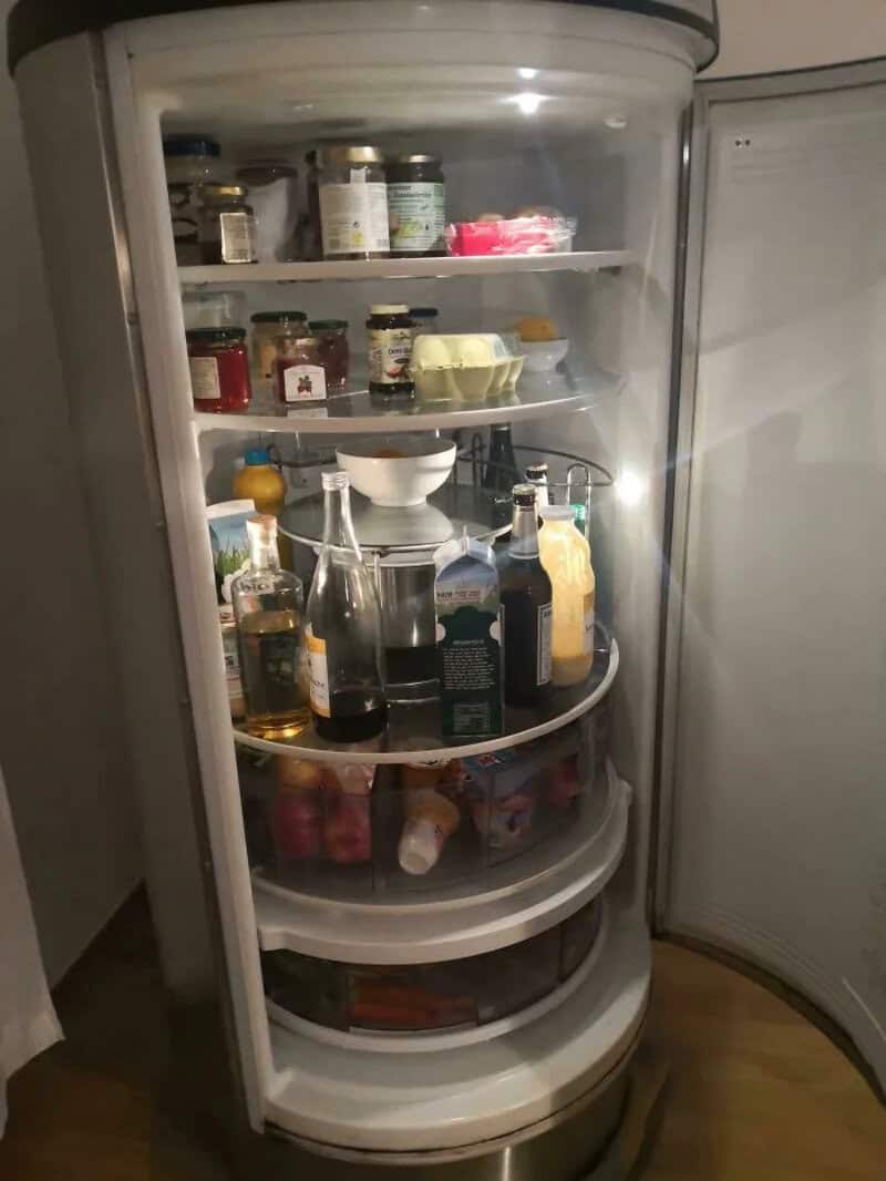 Refrigerator with bottles, jars, and food items inside, door open.