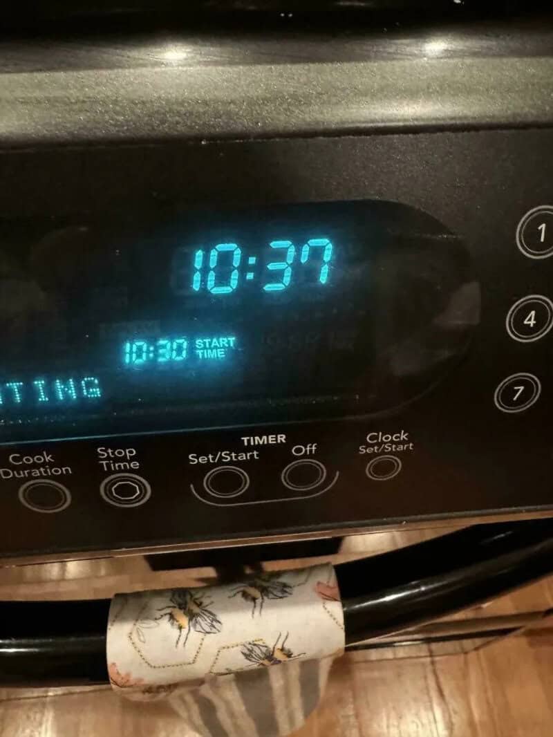 Digital oven clock showing 10:37 with a paper towel with bees underneath.