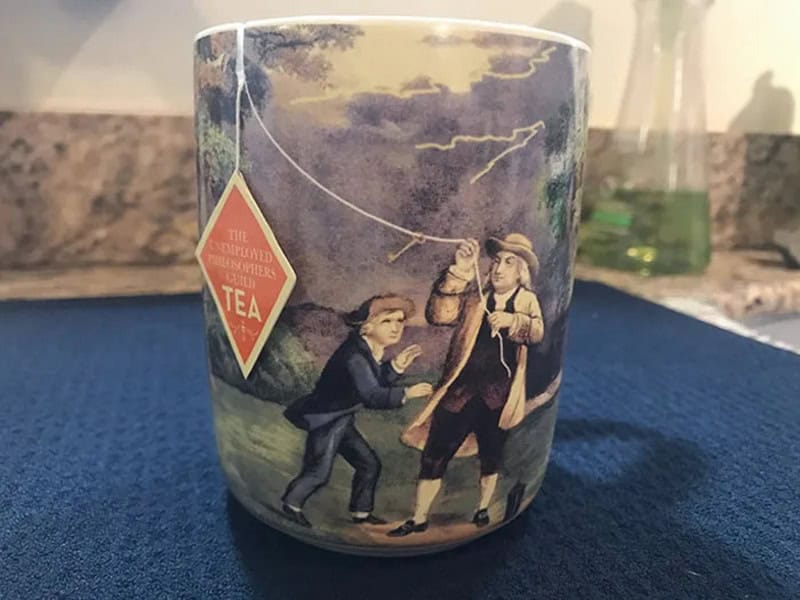 Vintage-style mug with children fishing, one holding a fishing rod, under a cloudy sky.