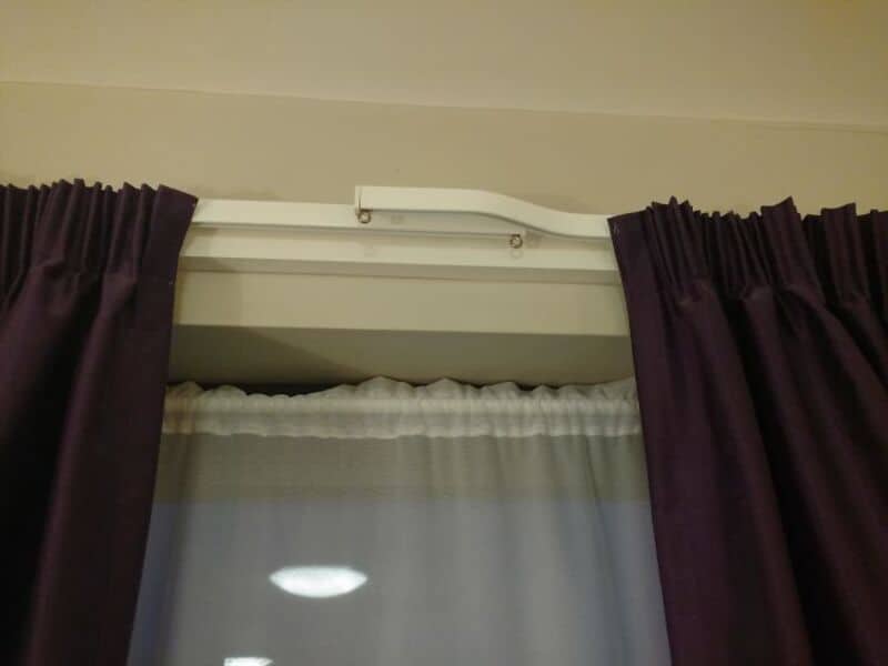 Curtain rail with a broken part and a makeshift fix using a paperclip.