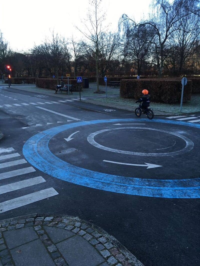 Circular bike lane with arrows and a child riding a bike in a park.