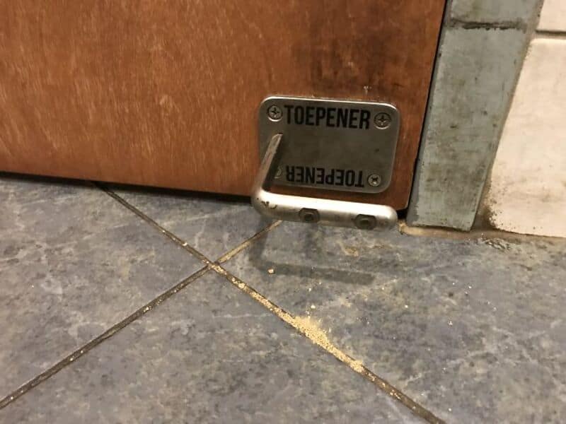 Door with a toe-operated door opener and a yellow powder on the floor.