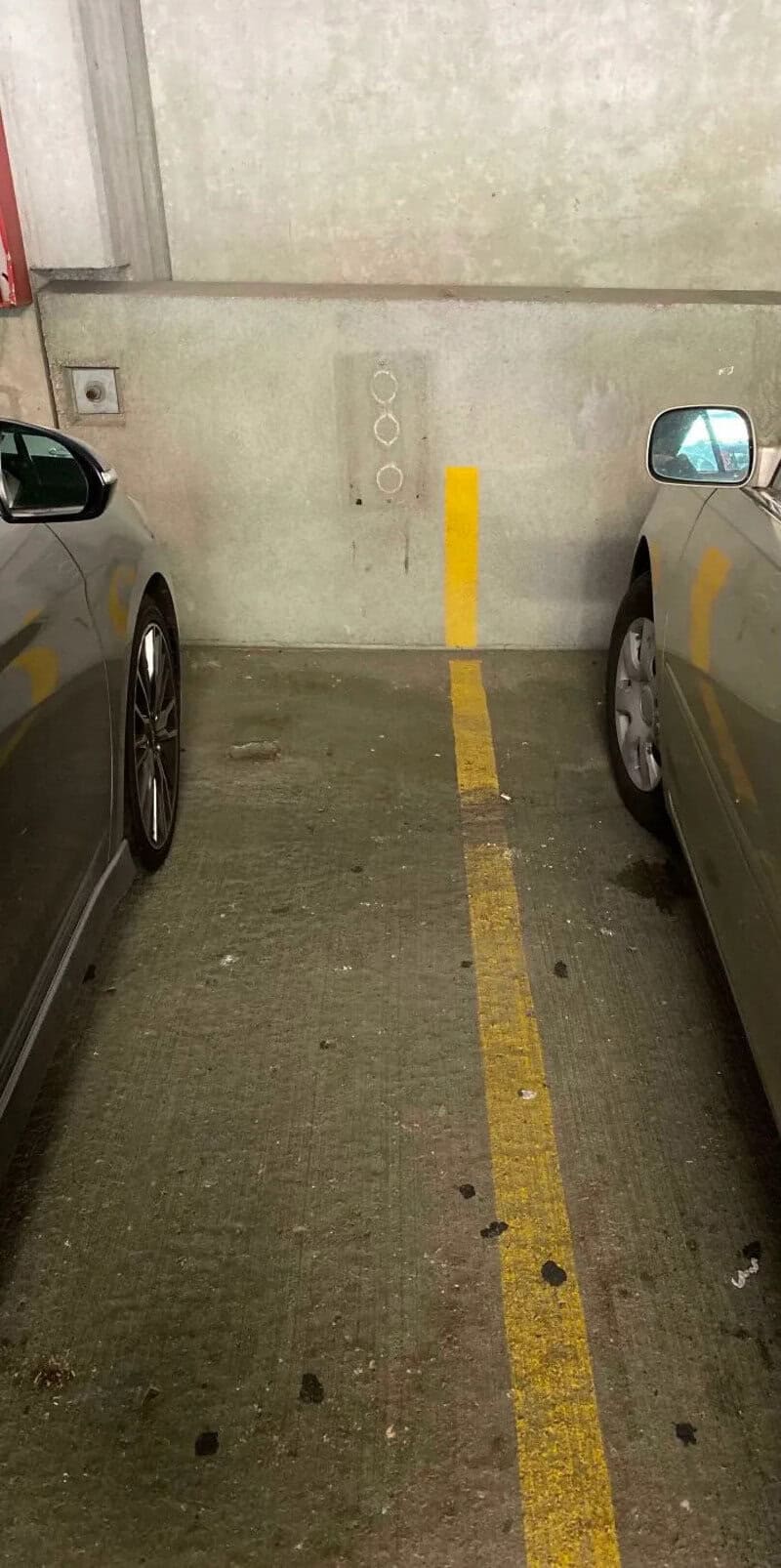 Parking lot with two cars and a yellow line in the middle.