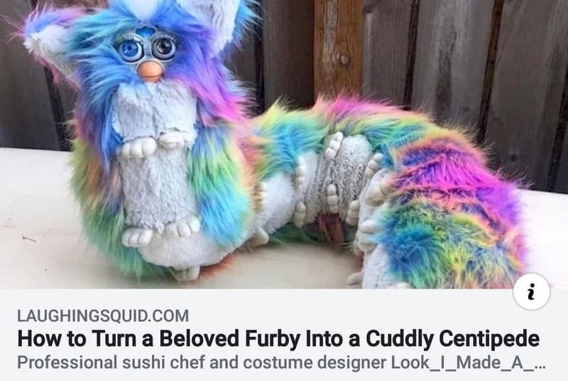 Colorful furry plush toy with big eyes and a rainbow tail, lying on a surface.