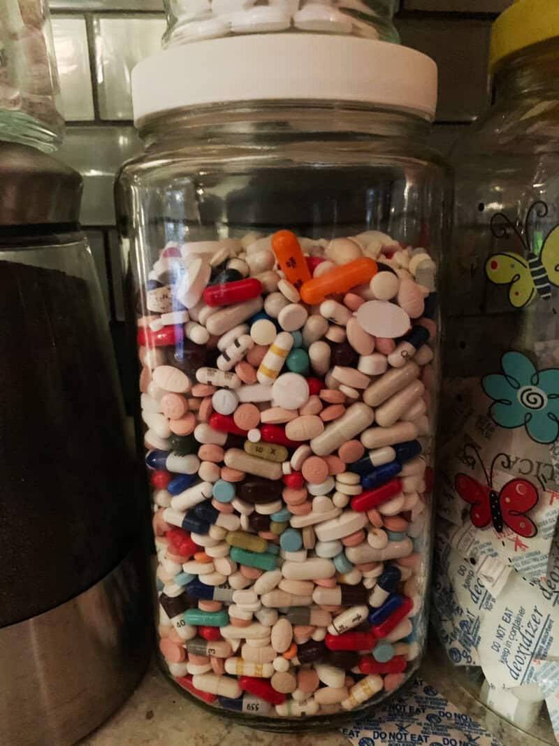 A jar filled with various pills and tablets, including capsules and tablets of different colors.