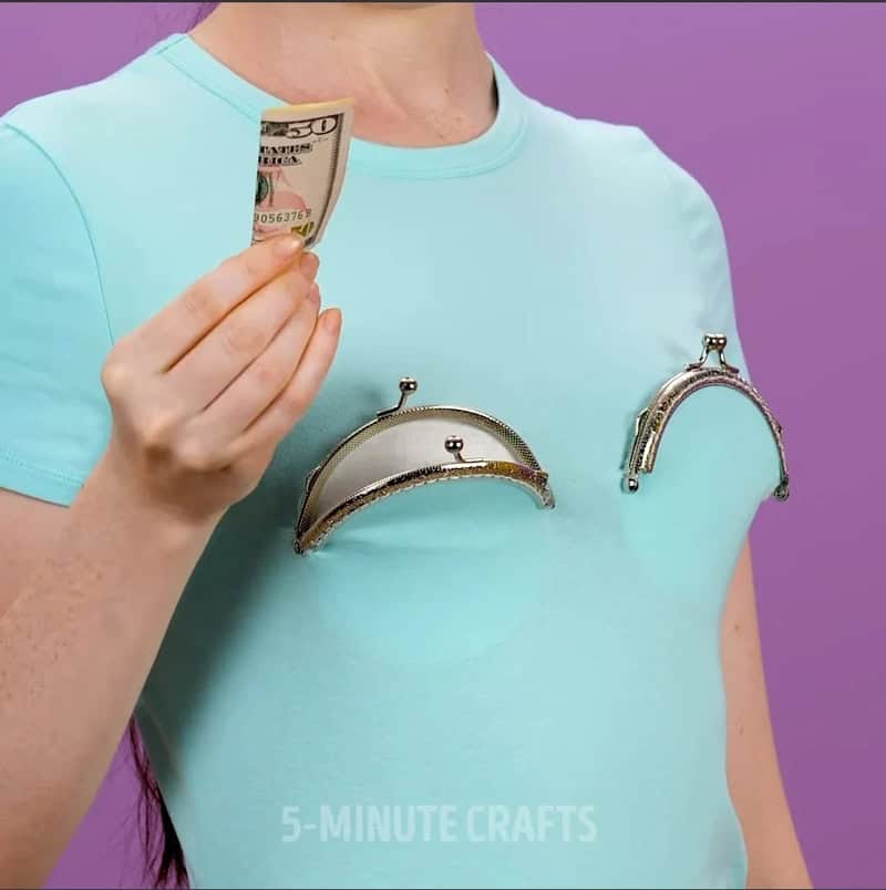 Person holding a $50 bill with empty coin purses on shirt.