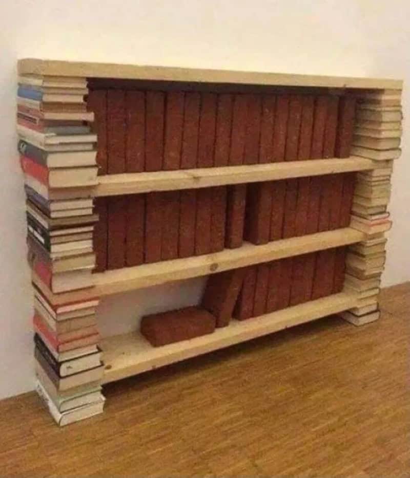 Bookshelf made of stacked books with three wooden shelves, some books are unevenly stacked.