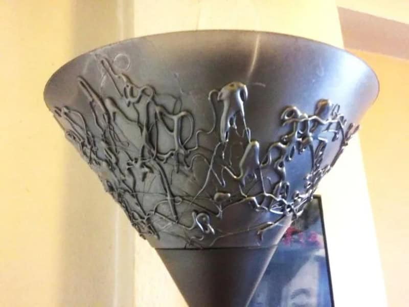 A black flower pot with tangled metal wires on it.