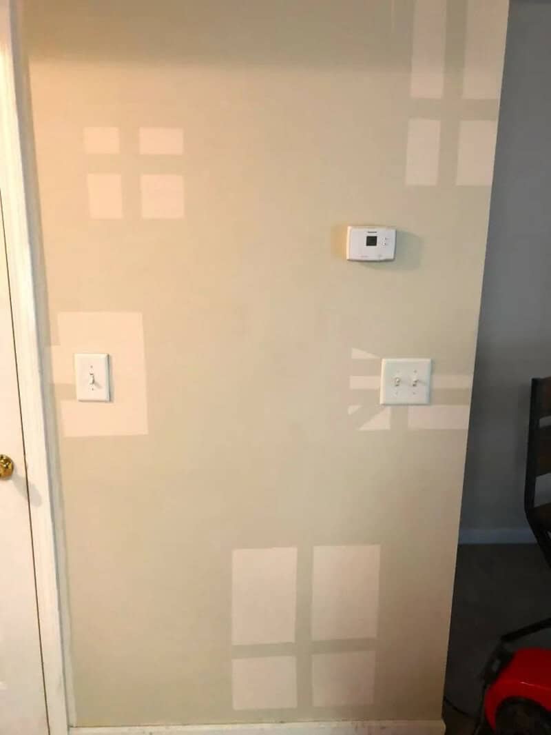 Wall with taped squares and thermostat, part of a DIY craft fail.