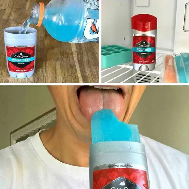 Person licking blue ice pop with fridge and drinks in background.