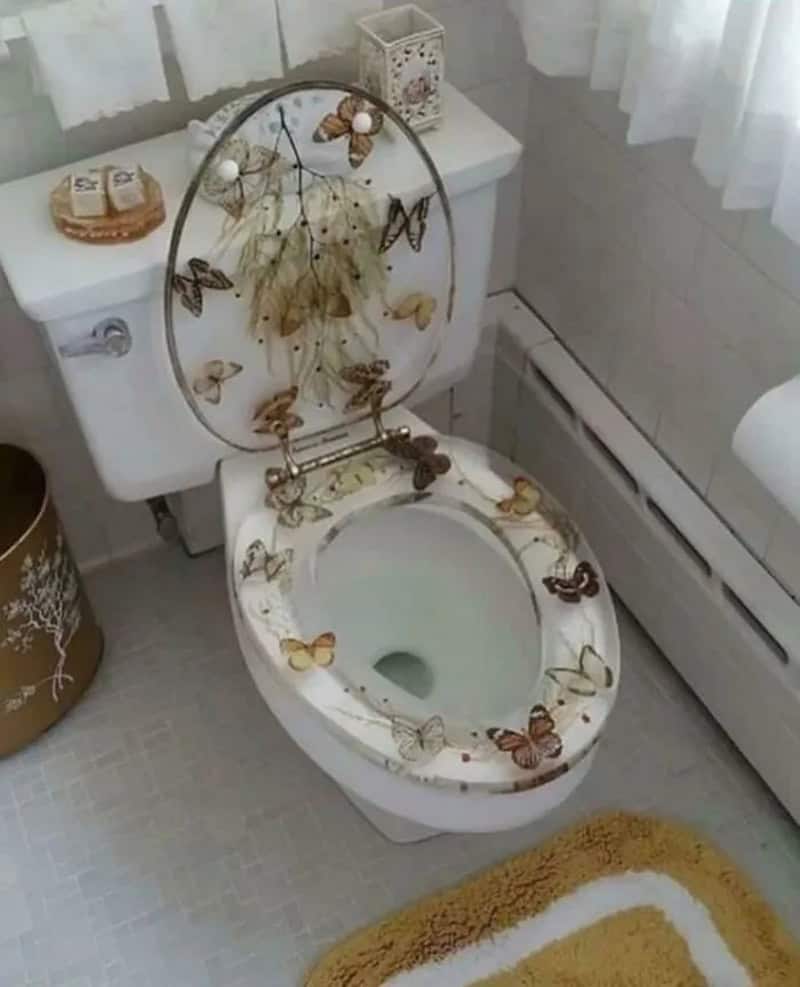 Toilet with butterfly and flower design on lid and seat, in a bathroom.