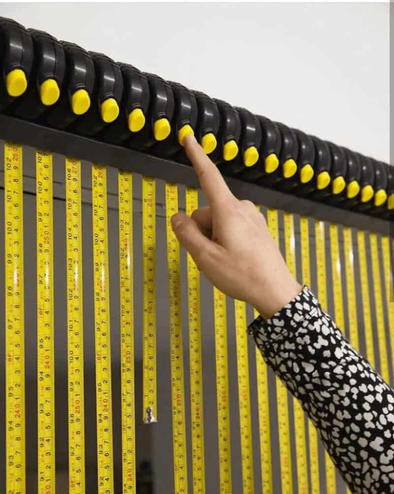 Person pressing a button on a black and yellow measuring device.