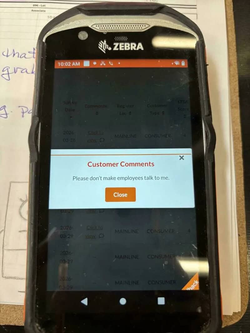 Zebra mobile device with a customer comment alert on screen, reading 'Please don't make employeesalt.