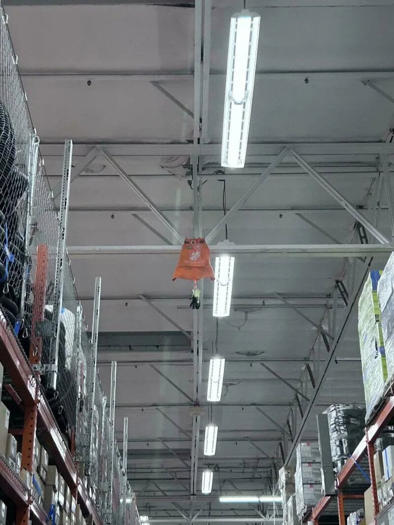Orange bag hanging from the ceiling in a hardware store aisle.
