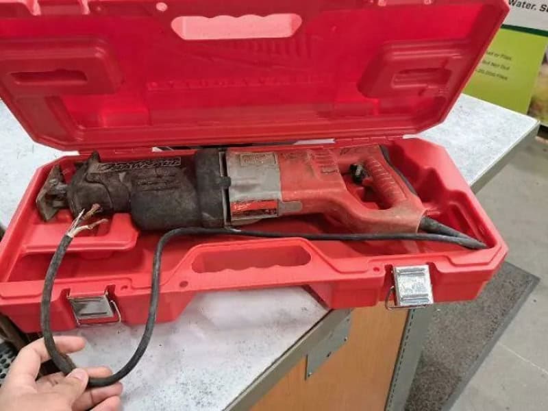 Red power tool in a red case on a workbench.