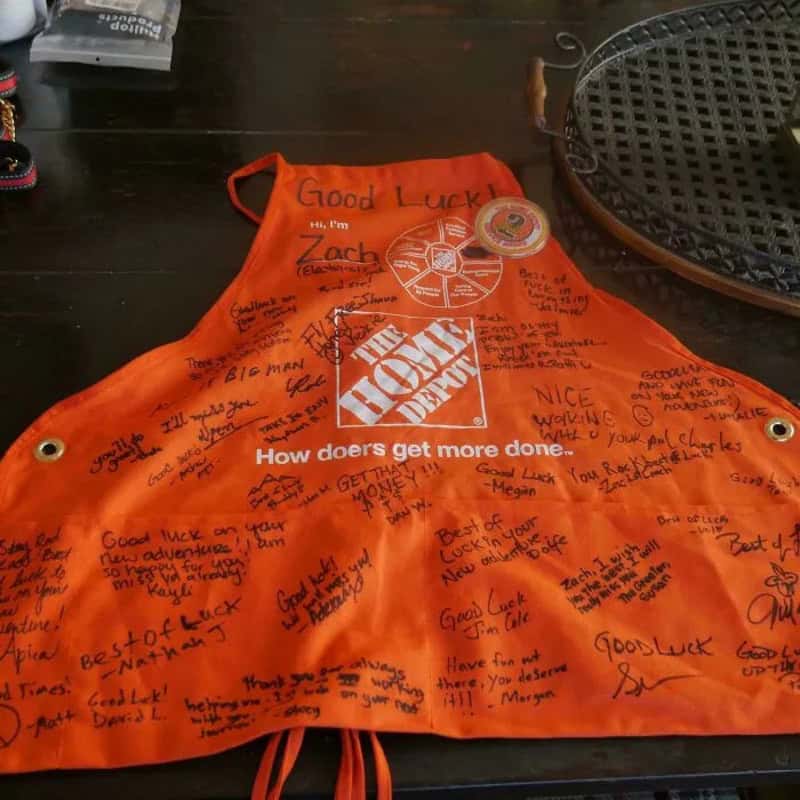 Orange apron with handwritten messages and signatures, The Home Depot logo visible.