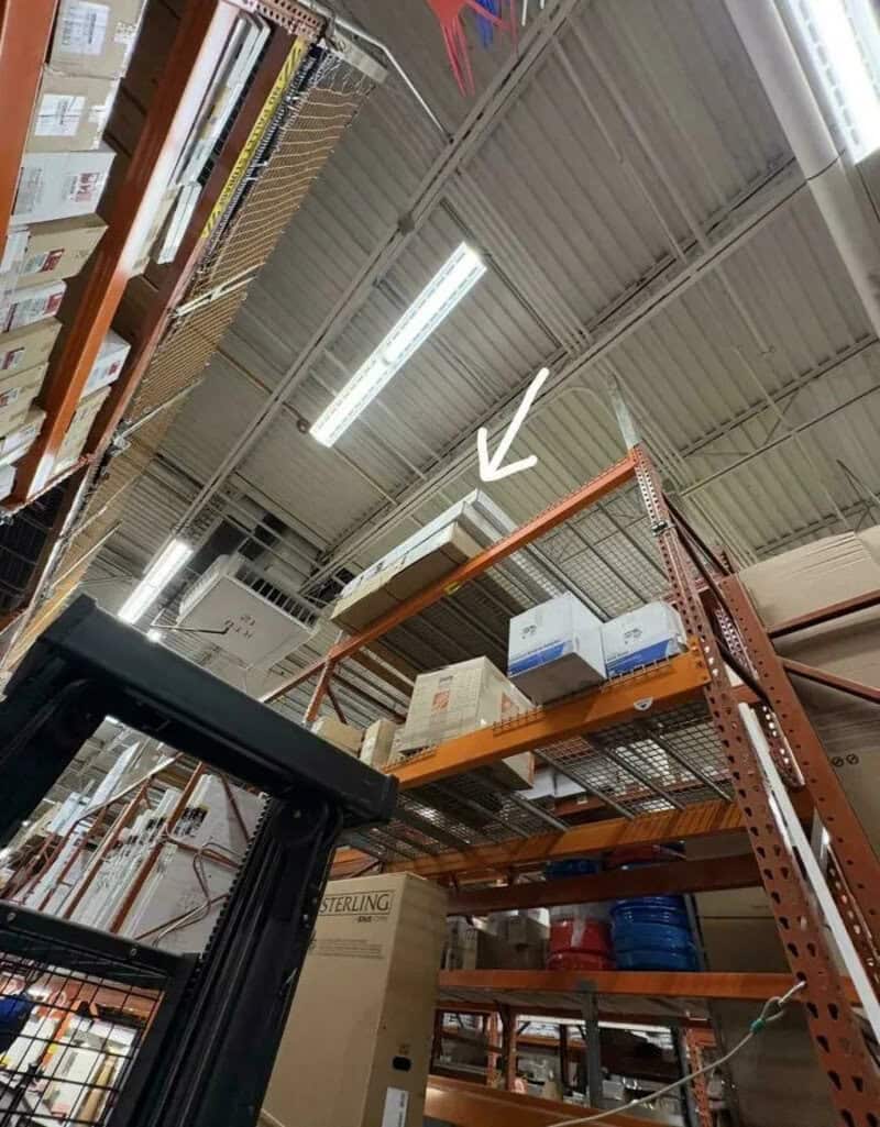 Shelves with boxes and a white arrow pointing to a box on the top shelf.