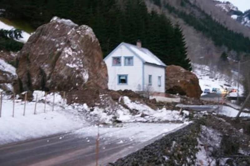 White house with large rocks and snow in a mountainous area.