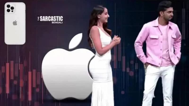 Two people standing near a large Apple logo and a smartphone display.