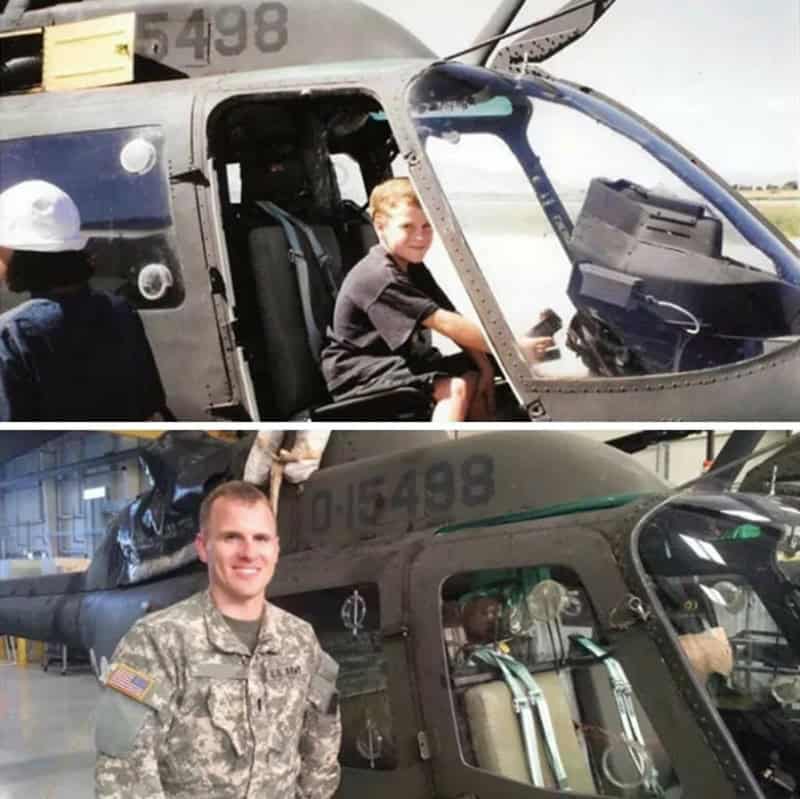 Young boy sitting in helicopter cockpit with a man in military uniform nearby.