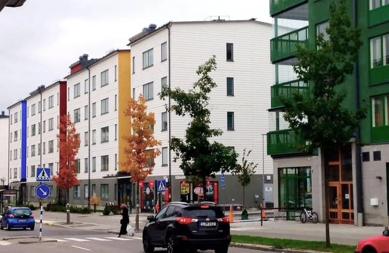 Colorful modern apartment buildings with trees and street scene.