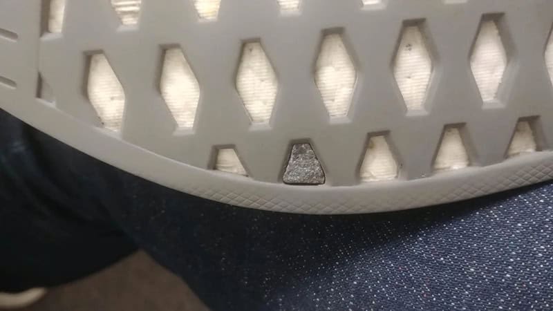 Close-up of a white plastic object with hexagonal holes and a dark background.