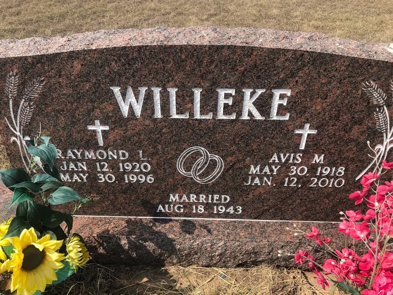 Gravestone with the name Willeke, wedding rings, and flowers.