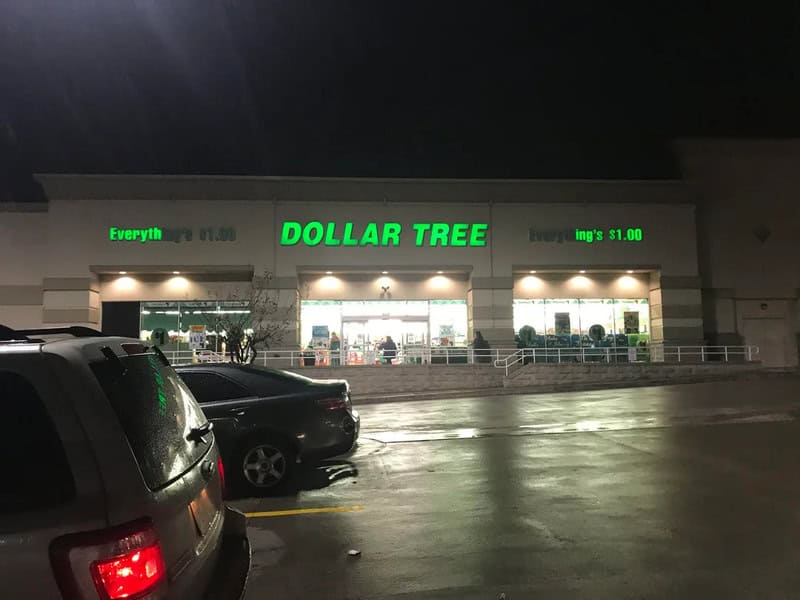 Dollar Tree store at night with green sign and parked cars in front.