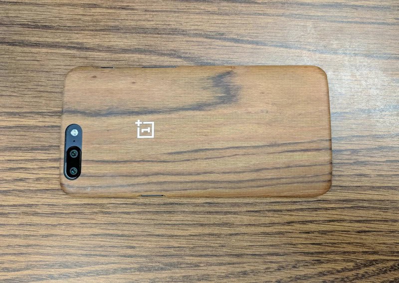OnePlus phone with a wooden back cover on a wooden surface.