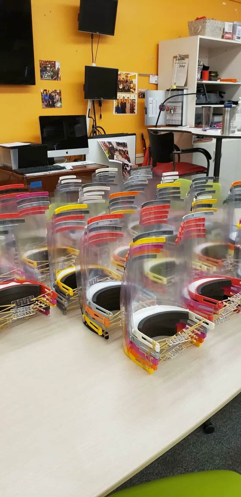 Multiple 3D printed bus models with transparent covers on a table.