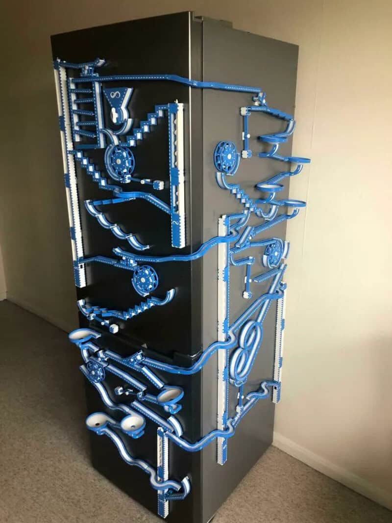 3D printed blue pipes and gears on a black cabinet, part of a mechanical display.