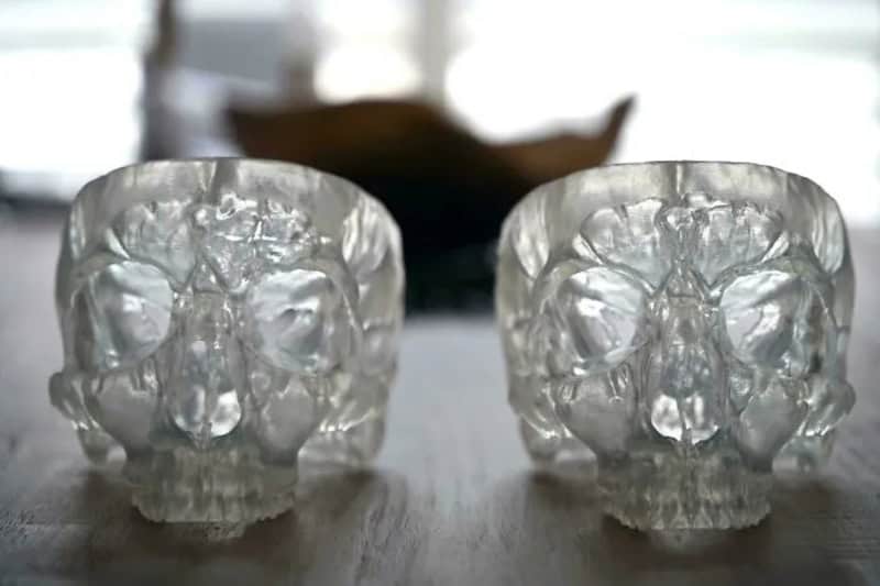 Two transparent skull-shaped objects on a wooden surface.