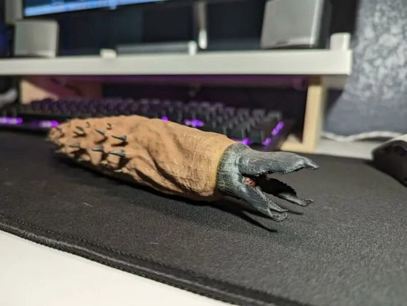 Deformed glove with black claws on a desk near a keyboard.