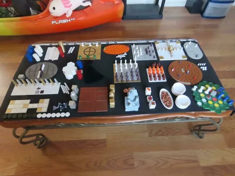 Table with various board game pieces and components for 3d printing.