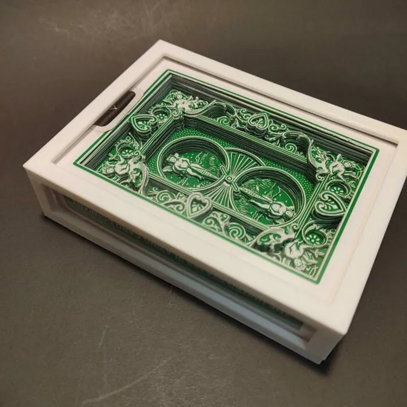 Green and white layered paper cutout of a car and decorative elements in a box.