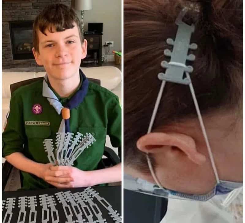 Boy with a scout uniform holding a 3D printed model of a spine.