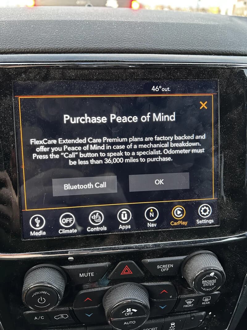 Car dashboard screen displaying an ad for Peace of Mind insurance plan.