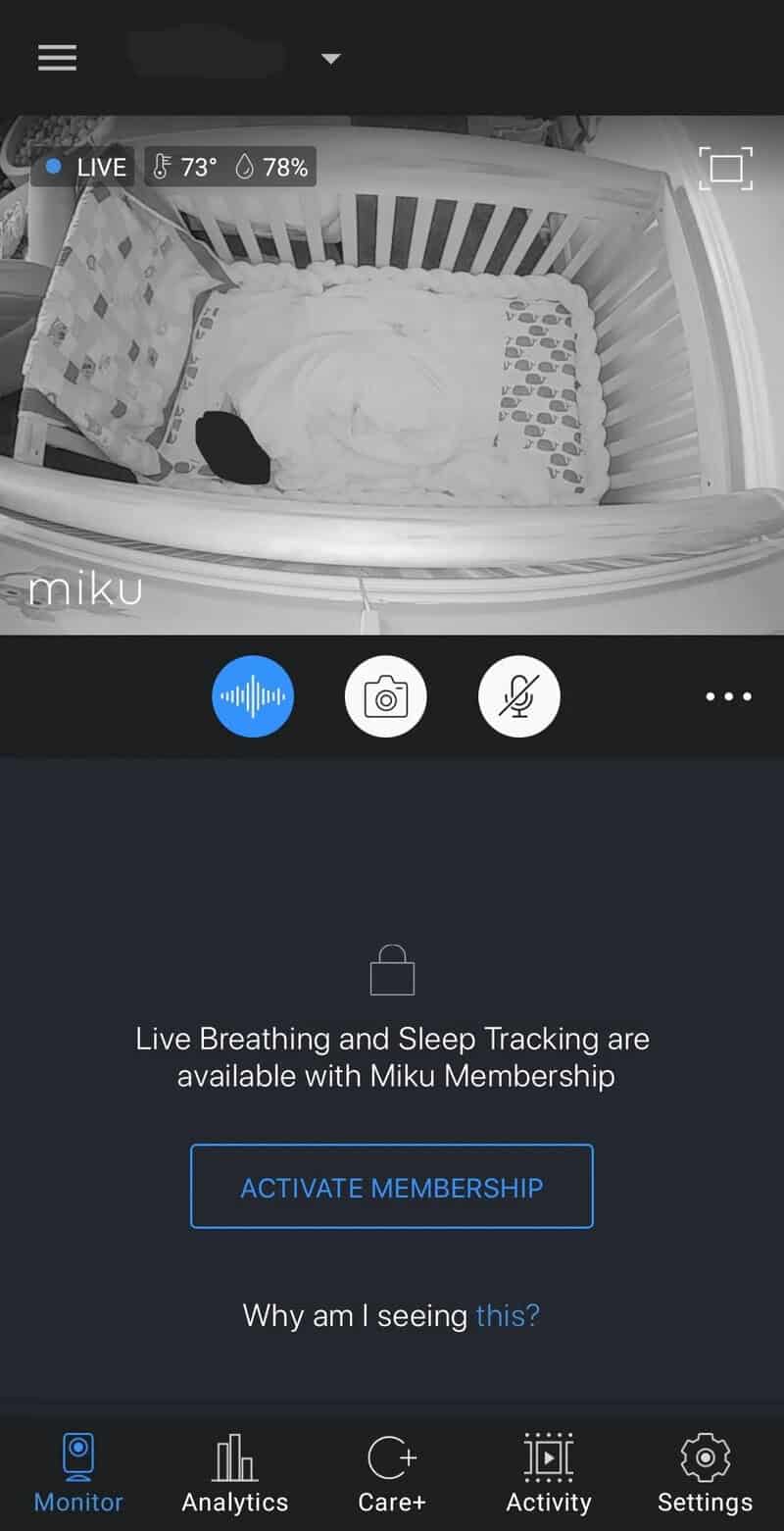 Baby sleeping in crib with sleep tracking app on phone screen.