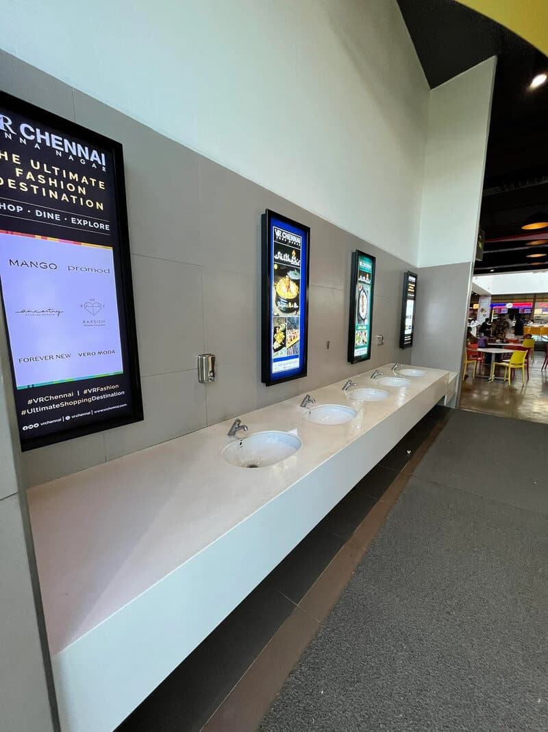 Digital advertising screens and sinks in a modern public space.
