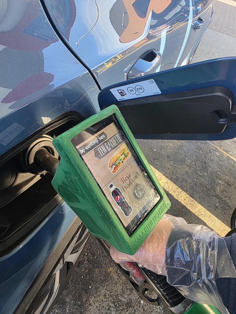 Person using a portable device to scan a car's QR code at a charging station.