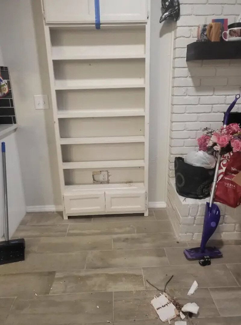 Empty white bookshelf with some debris on the floor in front.
