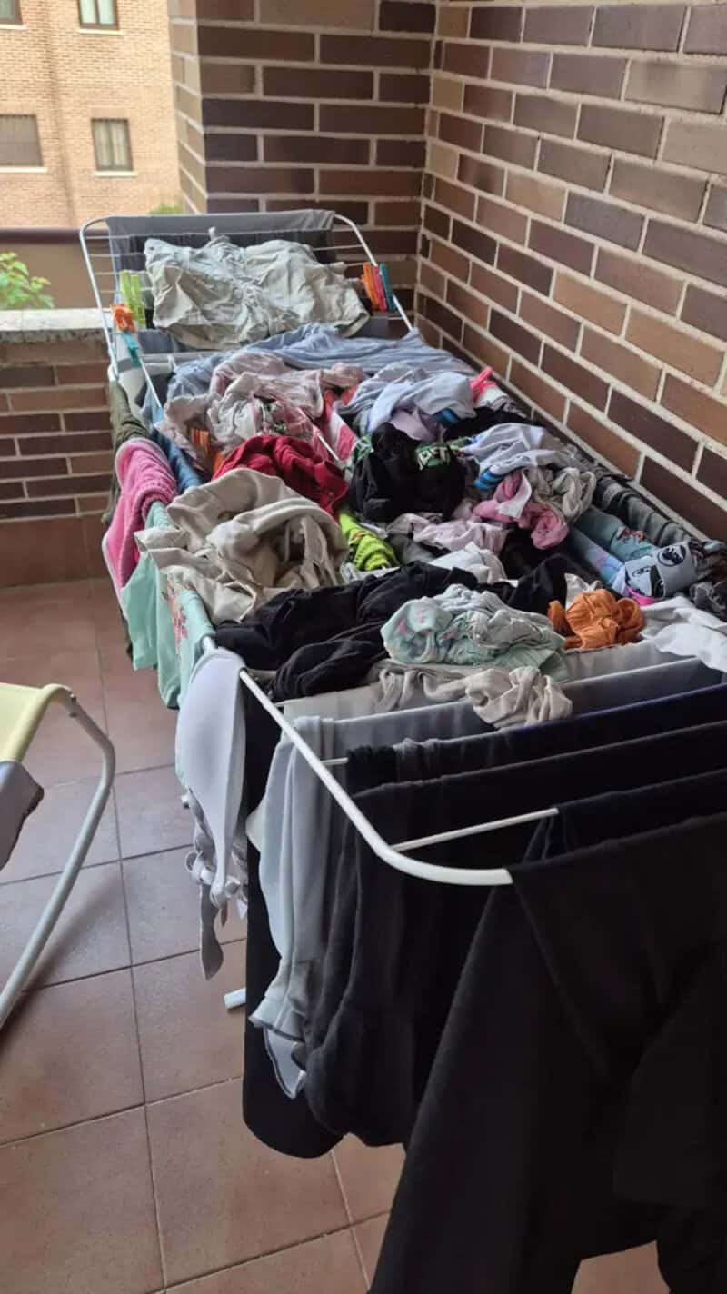 Clothes drying on a balcony with a brick wall background.