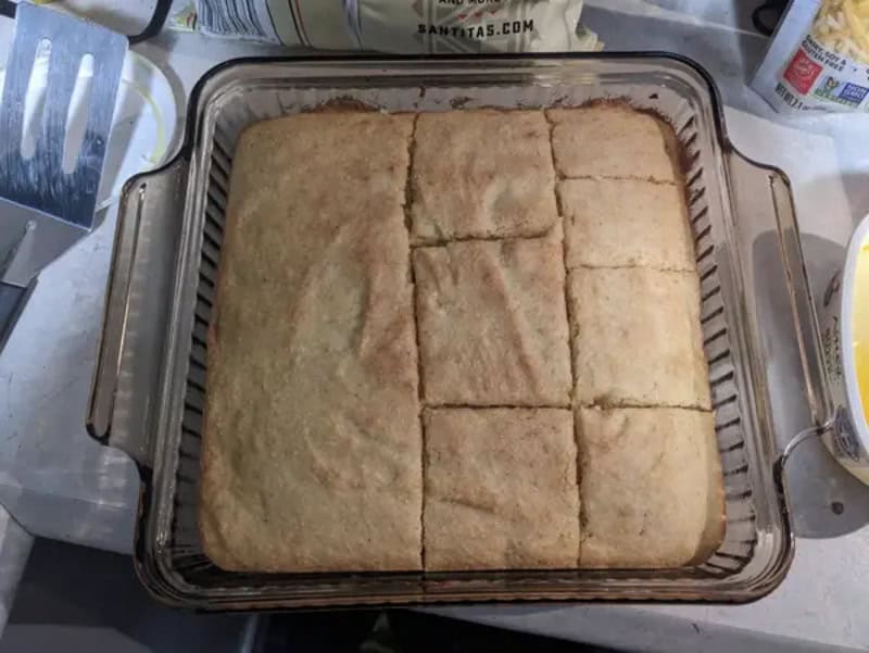Baked bread cut into squares in a baking dish on a kitchen counter.