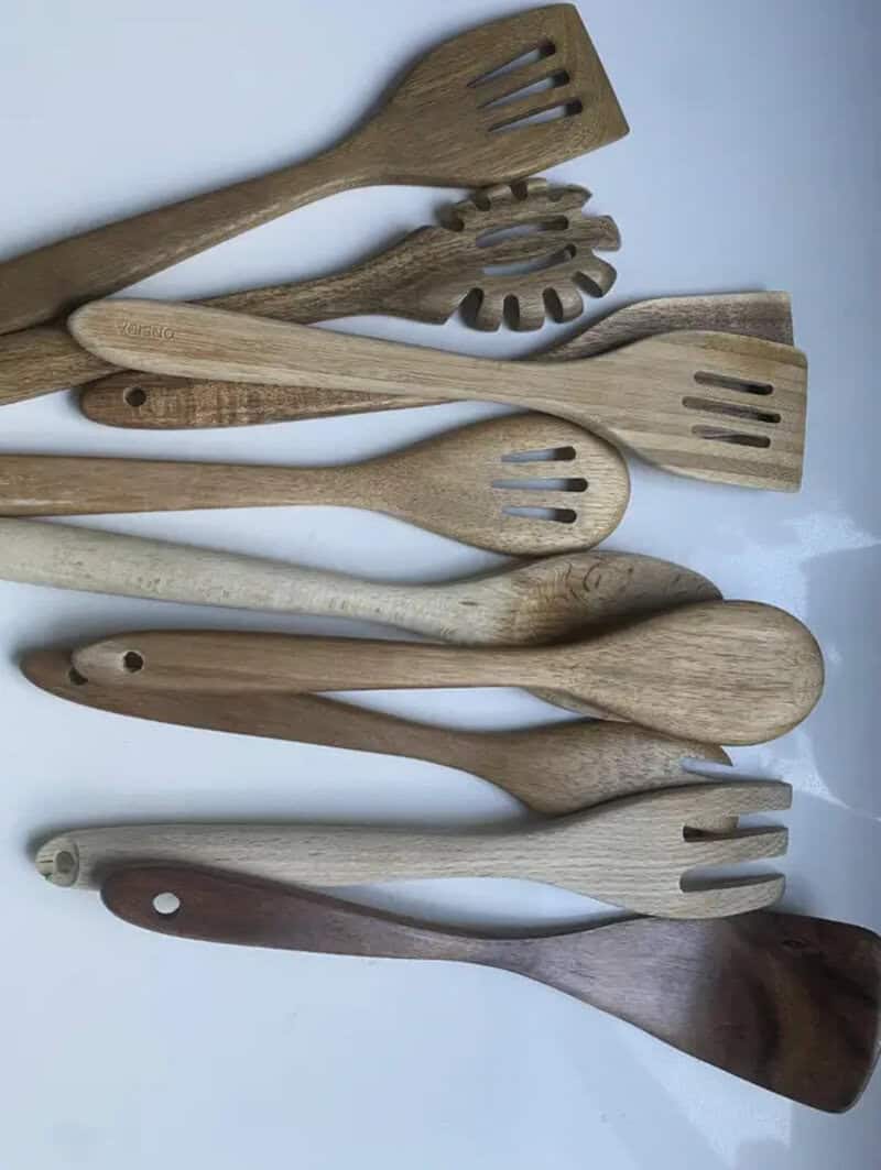 Collection of wooden spatulas and spoons on a white surface.