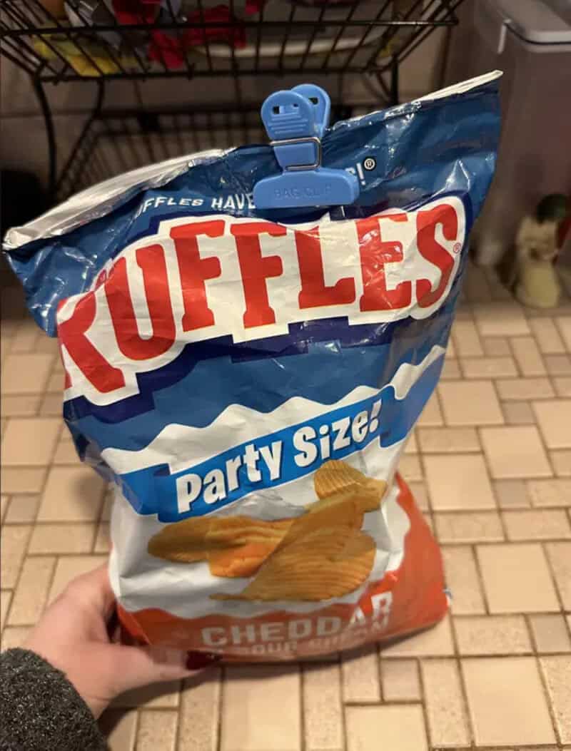 Bag of Ruffles Party Size Cheddar potato chips with a blue clip on top.