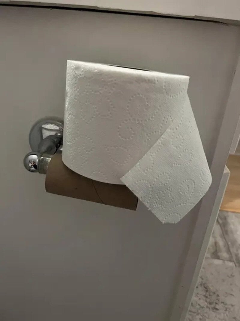 Toilet paper roll on holder with one sheet hanging down.